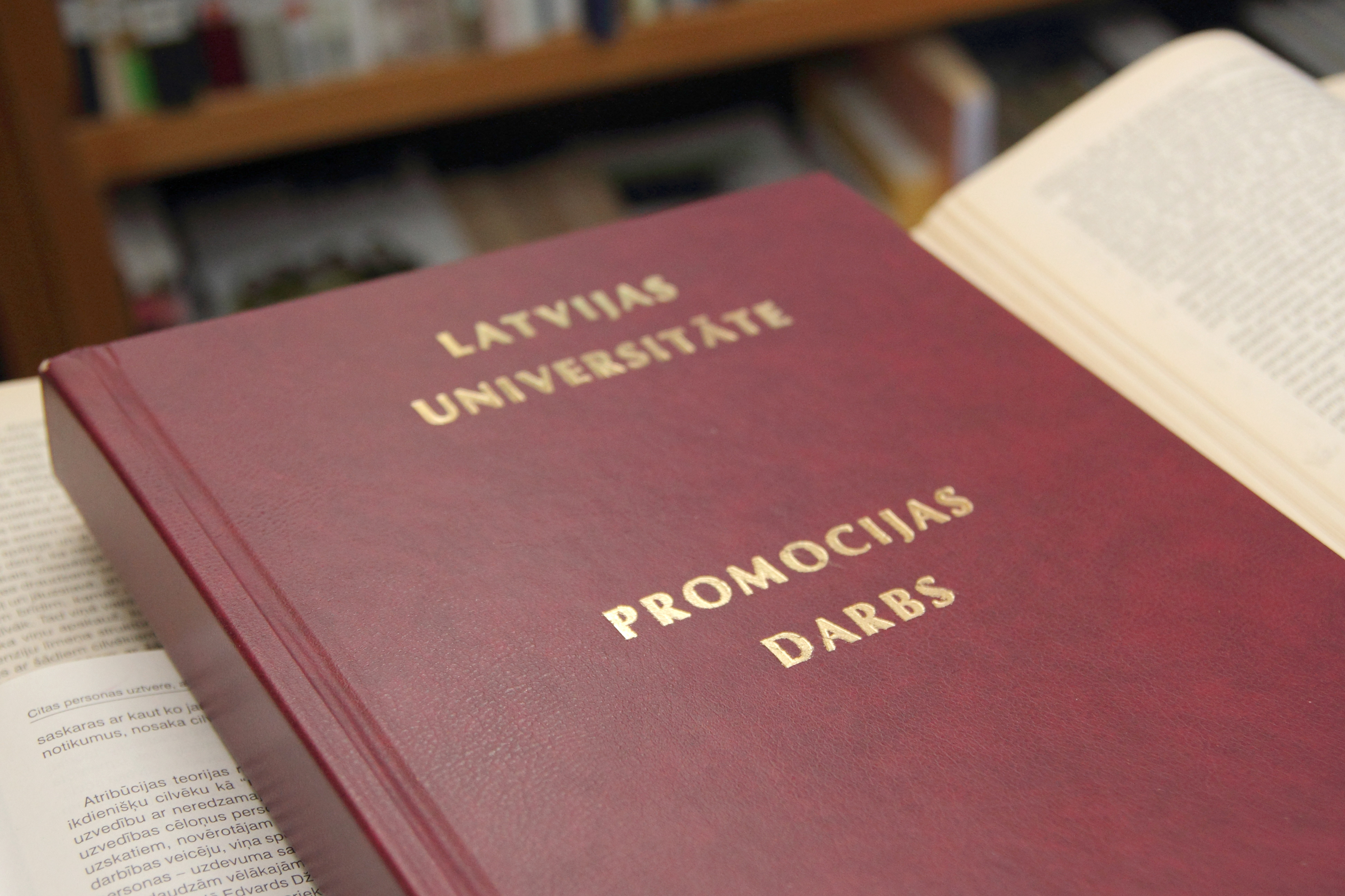 Tuvplāns promocijas darba tumši sarkanajam vākam ar zeltītiem uzrakstiem "Promocijas darbs"