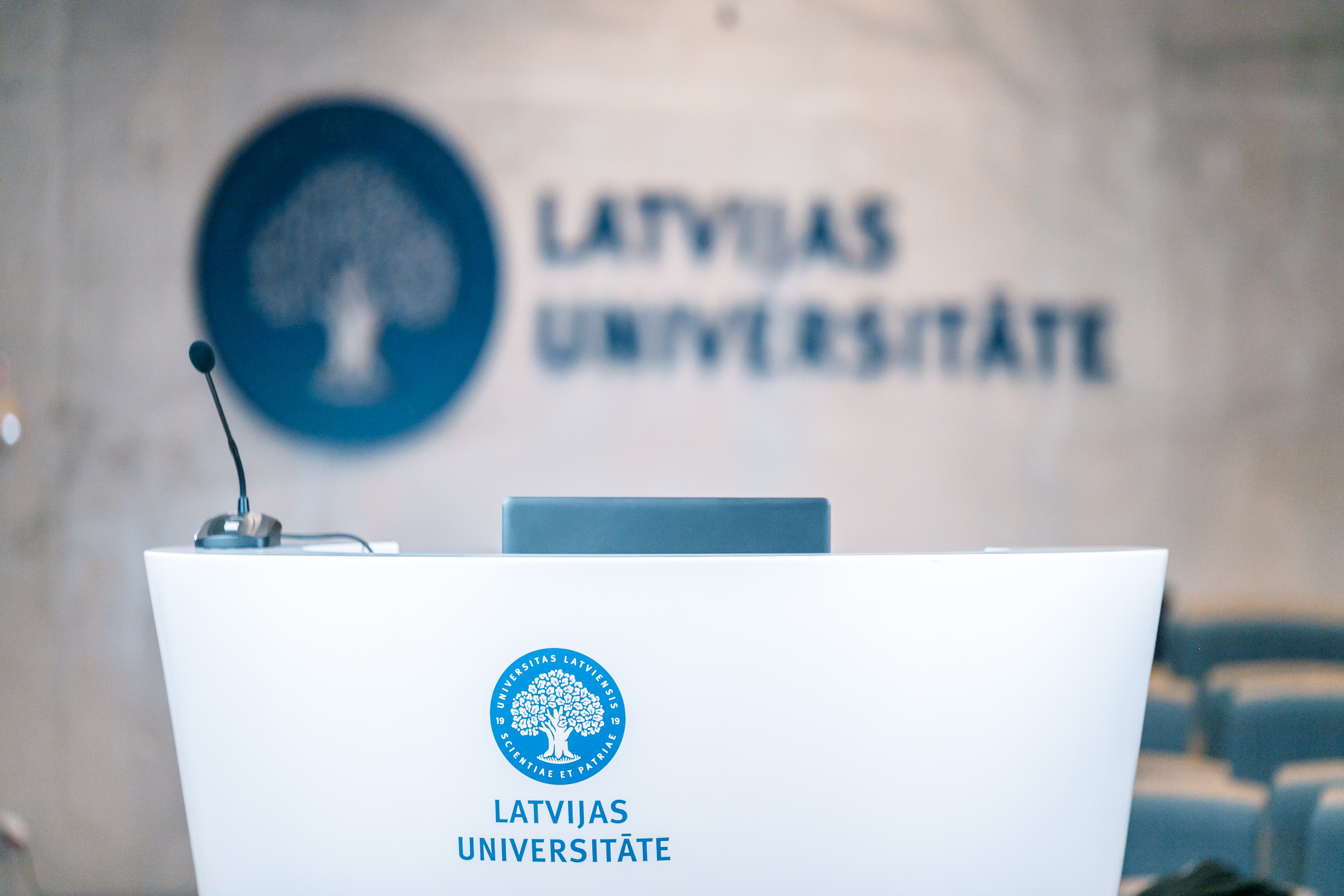 Latvijas universitātes logo uz sienas auditorijā Alfa